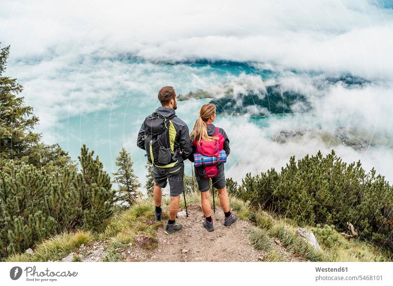 Young couple on a hiking trip in the mountains looking at view, Herzogstand, Bavaria, Germany human human being human beings humans person persons