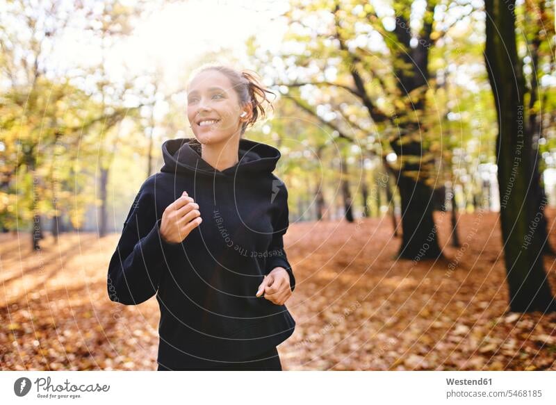 Young woman jogging in autumn forest run fall delight enjoyment Pleasant pleasure happy content Contented Emotion pleased Black Color Black Colour free time