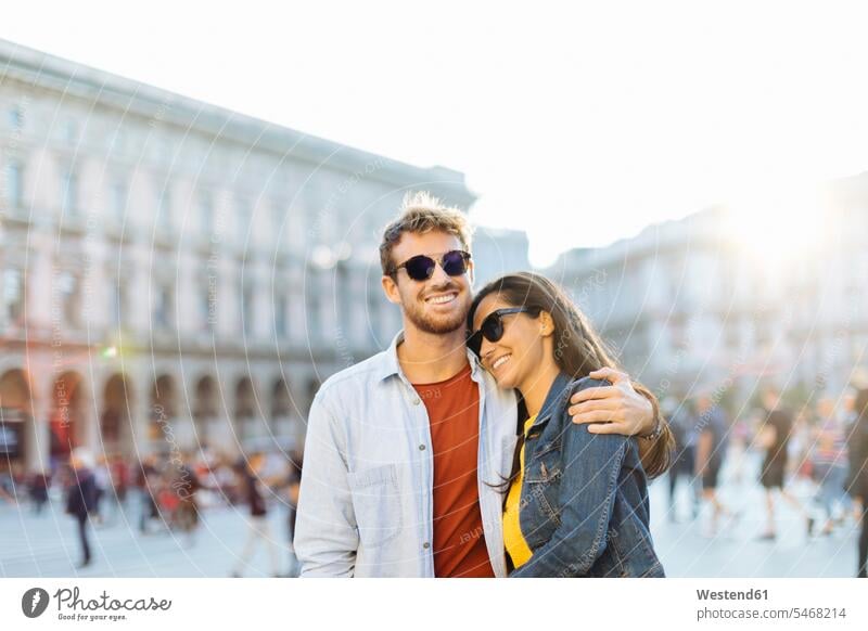 Happy young couple on a square in the city at sunset, Milan, Italy touristic tourists Eye Glasses Eyeglasses specs spectacles Pair Of Sunglasses sun glasses