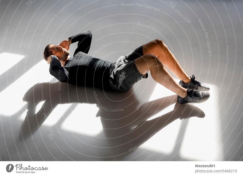 Athlete doing crunshes in sunlit studio exercise practising train training sports athletes Sportsman Sportsmen Sportspeople Sportsperson Force Power Strengthy