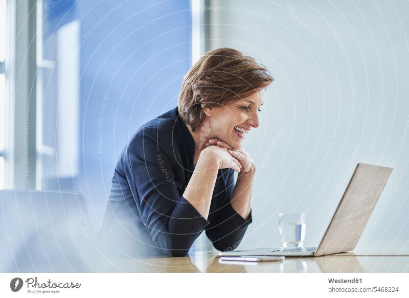 Happy businesswoman using laptop at desk in office Occupation Work job jobs profession professional occupation business life business world business person