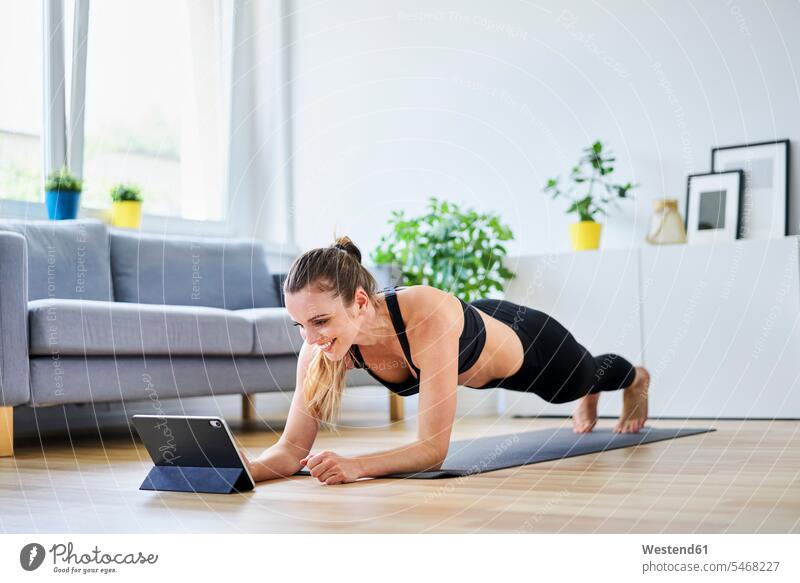 Smiling woman learning plank exercise on internet at home color image colour image indoors indoor shot indoor shots interior interior view Interiors