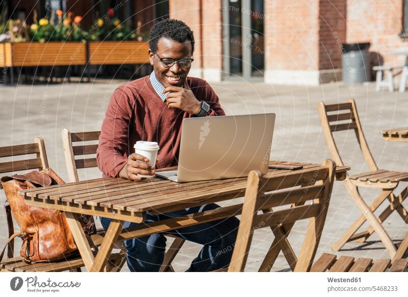 Young man using laptop in a coffee shop, drinking coffee computers Laptop Computer Laptop Computers laptops notebook Eye Glasses Eyeglasses specs spectacles