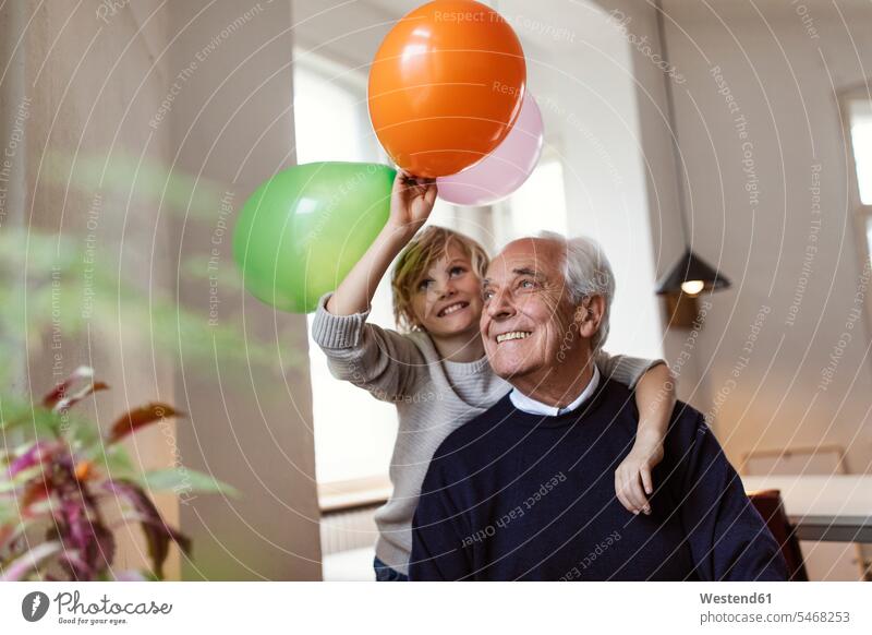 Happy grandfather and grandson playing with balloons at home generation windows jumper sweater Sweaters smile embrace Embracement hug hugging delight enjoyment