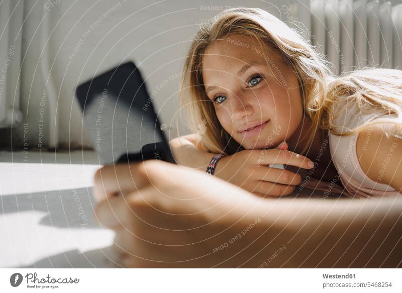Blond young woman lying on the floor using cell phone heater radiator telecommunication phones telephone telephones cell phones Cellphone mobile mobile phones