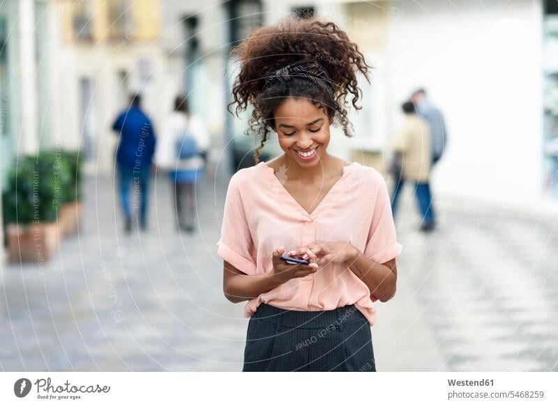 Smiling young woman using cell phone in the city females women mobile phone mobiles mobile phones Cellphone cell phones smiling smile town cities towns Adults