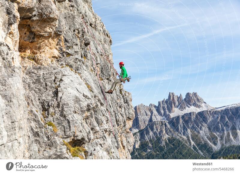 Italy, Cortina d'Ampezzo, man abseiling in the Dolomites mountains rock rocks climbing rock face rock wall escarpment climber rock climber Rappelling rappeling
