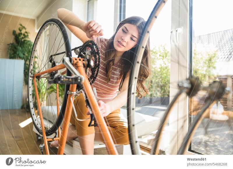 Young woman reparing bicycle at home bikes bicycles females women repairing Adults grown-ups grownups adult people persons human being humans human beings