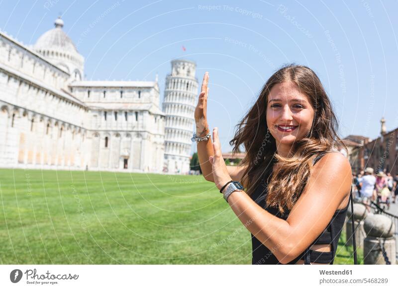Italy, Pisa, portrait of young woman posing with the Leaning Tower in background pose Posed portraits tower towers females women built structure buildings