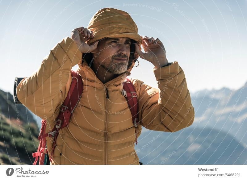 Austria, Tyrol, portrait of man with hooded jacket on a hiking trip in the mountains portraits men males mountain range mountain ranges hike Hooded Jackets