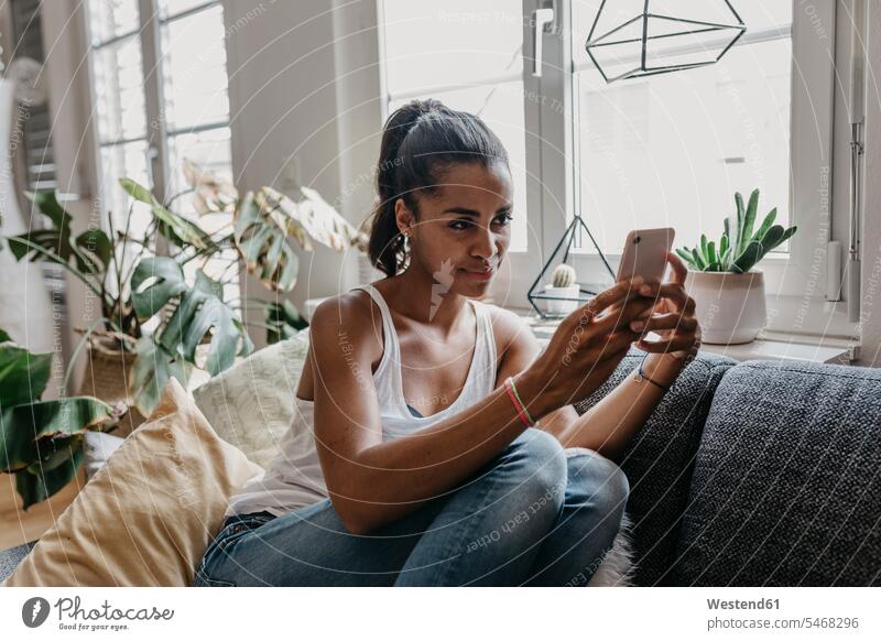 Portrait of young woman sitting on the couch at home taking selfie with mobile phone Selfie Selfies Smartphone iPhone Smartphones portrait portraits females