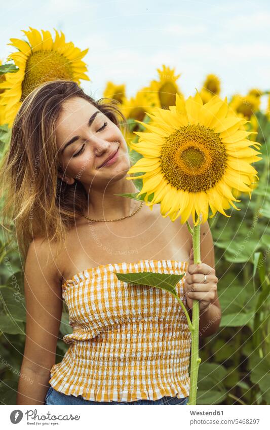 Young woman smiling holding a sunflower Sunflower Helianthus annuus Sunflowers Freedom Liberty free eyes closed closed eyes Eyes Shut Peace peacefulness