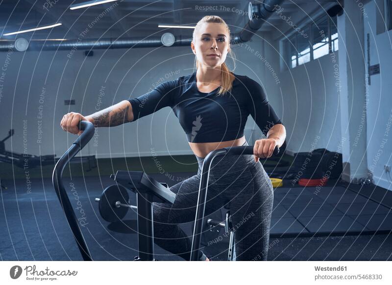 Athletic woman doing air bike workout at gym exercise exercises gyms Health Club females women sportive sporting sporty athletic Airbike Airbikes fitness sports