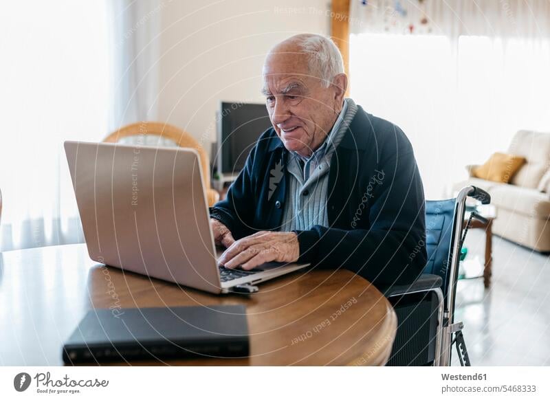 Portrait of content senior man in wheelchair using laptop at home human human being human beings humans person persons caucasian appearance caucasian ethnicity