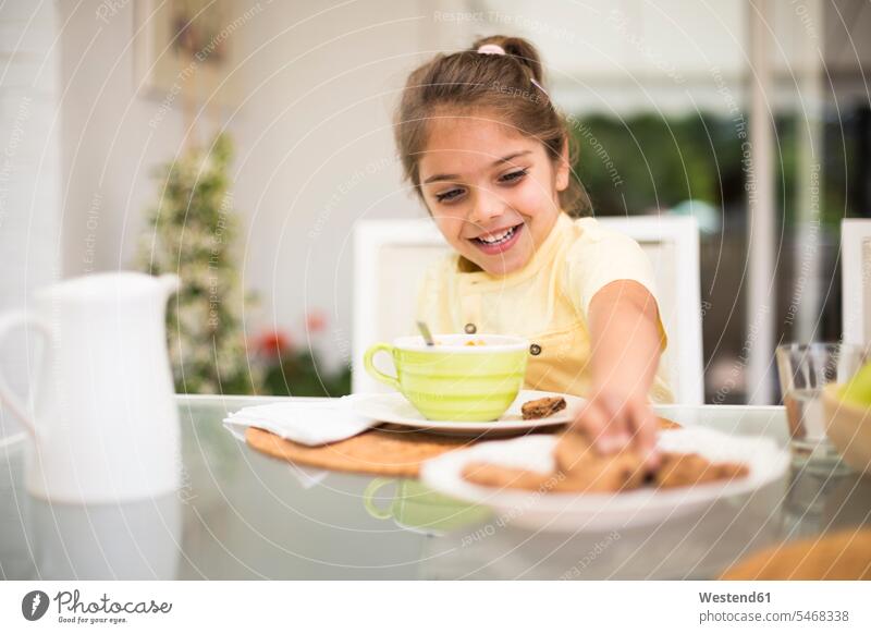 Happy little girl taking a cookie during breakfast at home take Biscuit Cookie Cooky Cookies Biscuits females girls Breakfast Pastry Pastries Sweet Food sweet