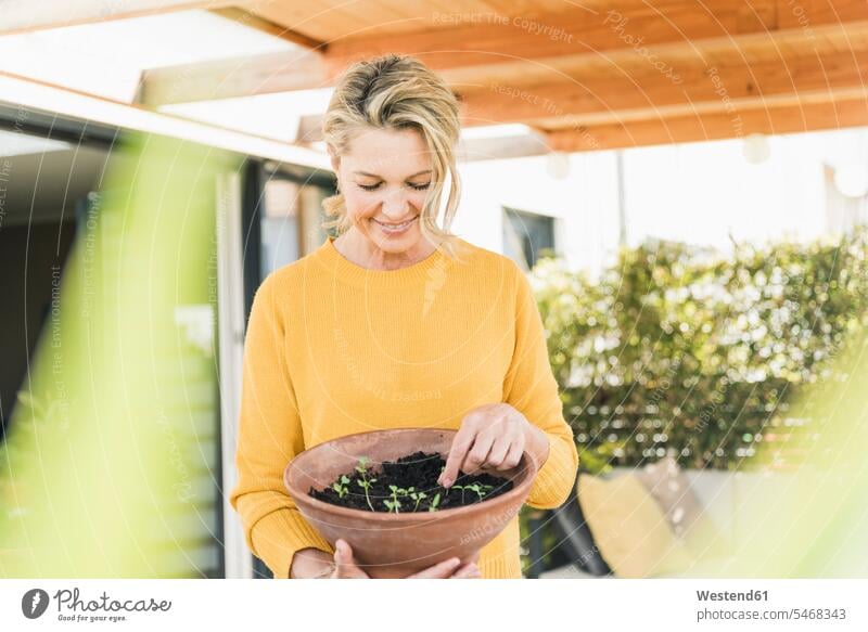 Portrait of mature woman with sprouts in a bowl on terrace jumper sweater Sweaters touch relax relaxing smile delight enjoyment Pleasant pleasure indulgence