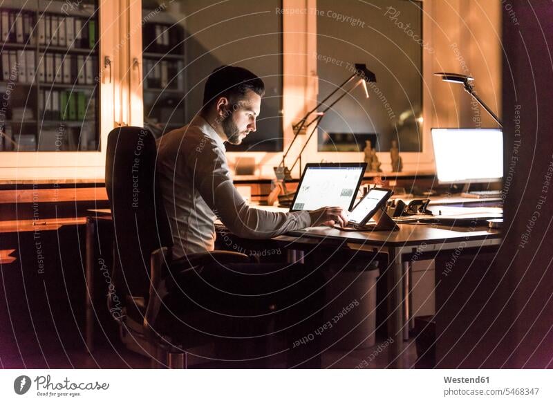 Businessman working at desk in office at night Business man Businessmen Business men offices office room office rooms by night nite night photography At Work