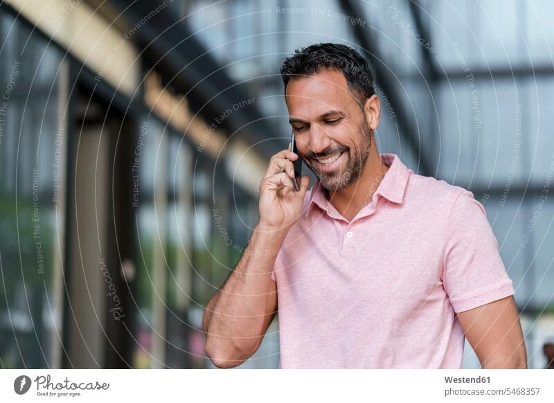 Smiling man on cell phone in the city Joy enjoyment pleasure Pleasant delight on the phone call telephoning On The Telephone calling talking conversations