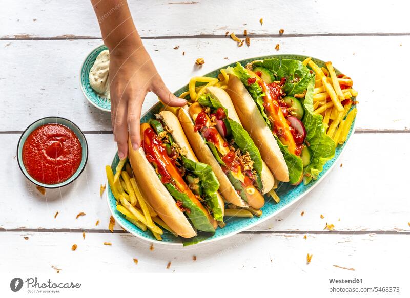 Hot dogs with french fries, ketchup and mayonnaise, hand taking an hot dog Hotdog Hot-Dogs hot dogs Hotdogs Unhealthy Eating unhealthy eating human hand hands