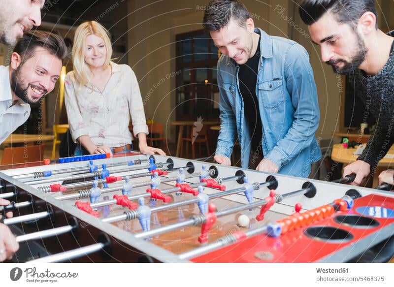 Happy colleagues playing foosball in office human human being human beings humans person persons caucasian appearance caucasian ethnicity european adult