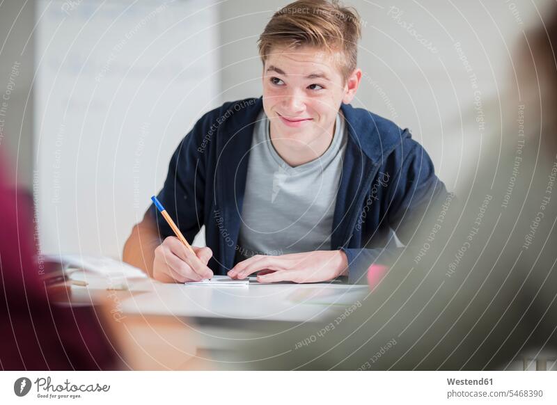 Smiling teenage boy taking notes in class Teenager Teens teenagers smiling smile school class Classroom class rooms Schoolroom classrooms schools making a note