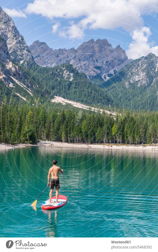 Male tourist paddleboarding on turquoise Pragser Wildsee, Dolomites, Alto Adige, Italy color image colour image outdoors location shots outdoor shot