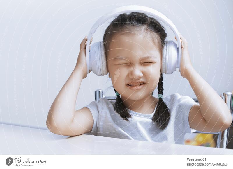 Portrait of little girl listening music with white cordless headphones Cordless portrait portraits headset hearing females girls colour colours child children