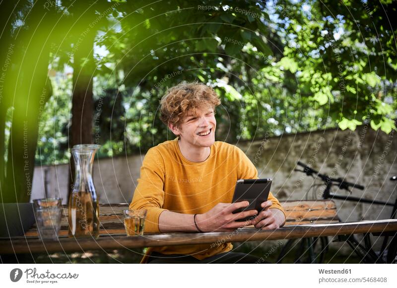 Portrait of young man sitting at beer table in garden with digital tablet human human being human beings humans person persons caucasian appearance