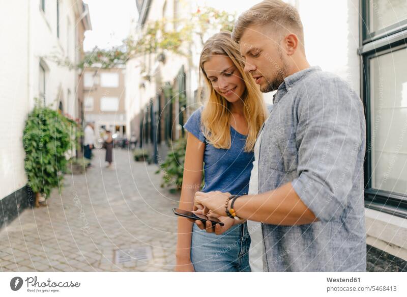 Netherlands, Maastricht, young couple looking at cell phone the city mobile phone mobiles mobile phones Cellphone cell phones twosomes partnership couples town