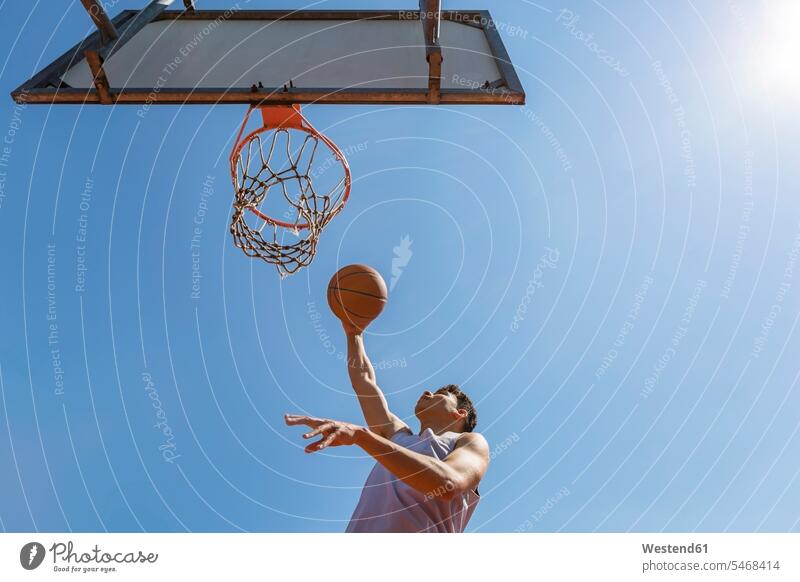 Young man throwing the basketball clear sky copy space cloudless jumping Leaping Motivation Incentive motivating Motivations agility agile active fitness