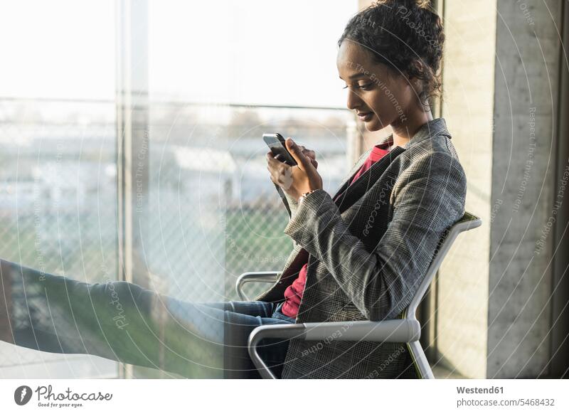 Young businesswoman using cell phone at the window in office Occupation Work job jobs profession professional occupation human human being human beings humans