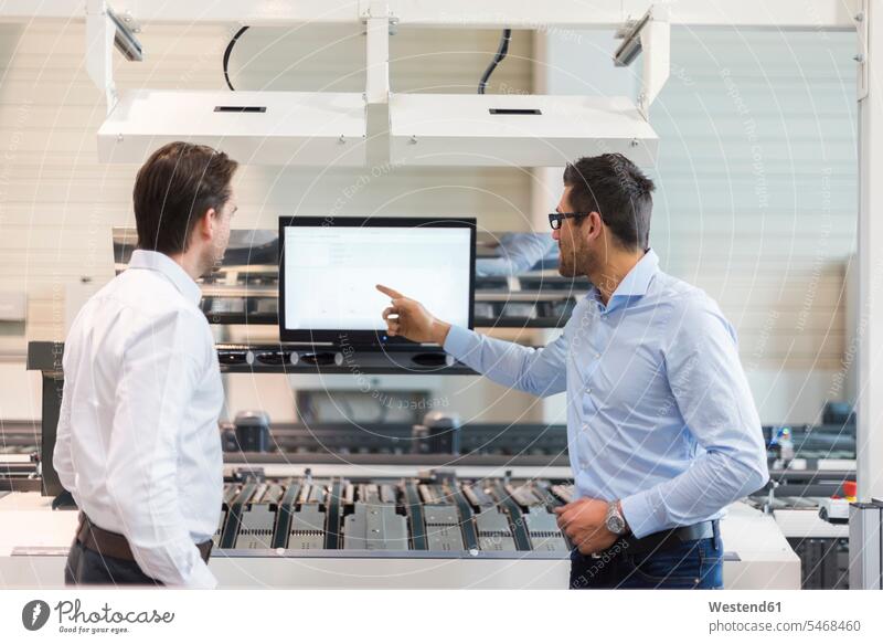Two businessmen talking at screen in modern factory factories speaking contemporary screens monitor monitors Businessman Business man Businessmen Business men