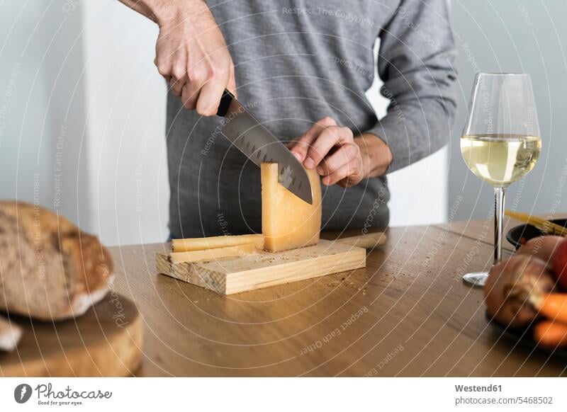 Close-up of man cutting cheese on kitchen counter jumper sweater Sweaters colour colours grey at home Lifestyle Alimentation food Food and Drinks Nutrition