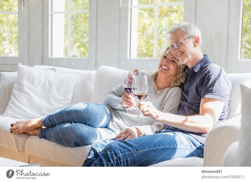 Mature couple relaxing on the couch with red wine having fun settee sofa sofas couches settees Fun funny twosomes partnership couples Red Wine Red Wines