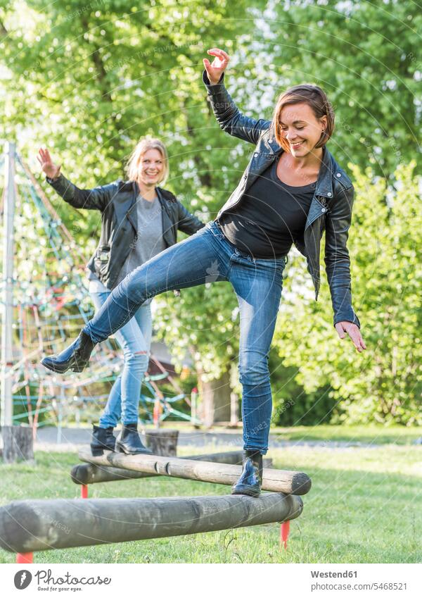 Two friends having fun on playground mate female friend pants Trouser Denim Jeans balanced Equilibrium smile delight enjoyment Pleasant pleasure Cheerfulness