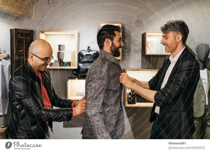 Two men working on new stylish look for handsome man in showroom customer clientele clients customers men's fashion shop modern contemporary males people
