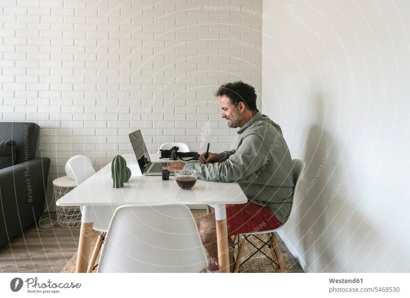 Man sitting at table working on graphics tablet and laptop human human being human beings humans person persons caucasian appearance caucasian ethnicity