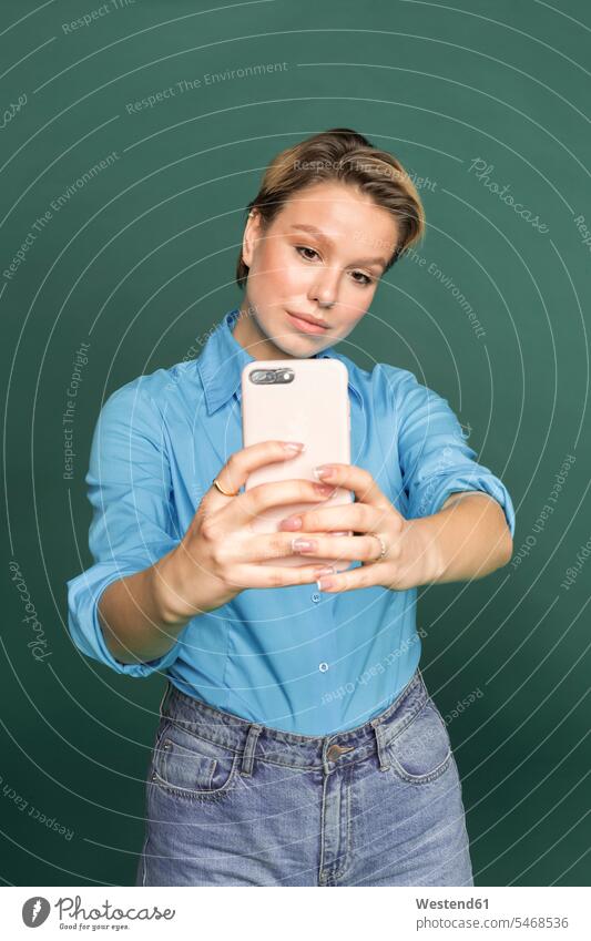 Portrait of young woman taking selfie with smartphone in front of green background females women Smartphone iPhone Smartphones Selfie Selfies portrait portraits