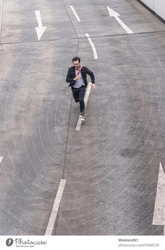 Businessman running on road with arrow signs Dedication Engagement dedicated Eager Input eagerness Commitment young entrepreneur young entrepreneurs