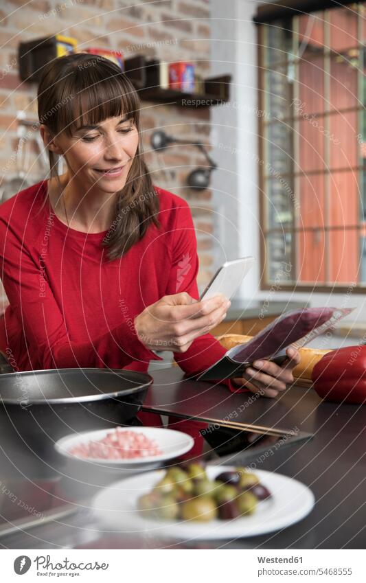 Woman in kitchen scanning products with her smartphone checking Test testing Check Smartphone iPhone Smartphones domestic kitchen kitchens mobile phone mobiles