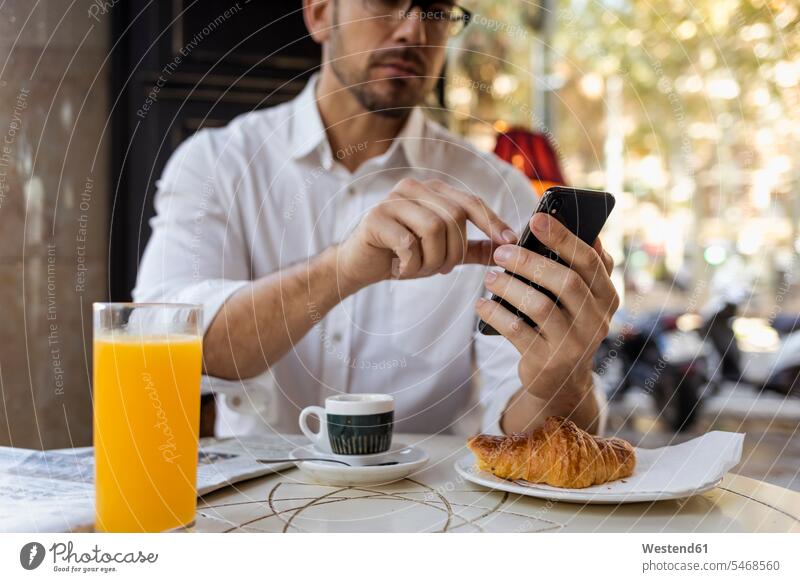 Businessman having breakfast in a cafe and using cell phone Breakfast Business man Businessmen Business men mobile phone mobiles mobile phones Cellphone