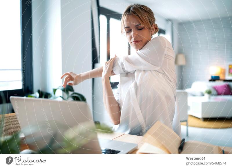 Tired woman stretching while working at home color image colour image indoors indoor shot indoor shots interior interior view Interiors businesswoman