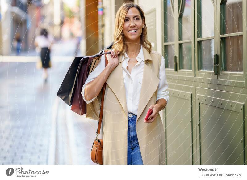 Woman carrying shopping bag while standing at footpath in city color image colour image outdoors location shots outdoor shot outdoor shots day daylight shot