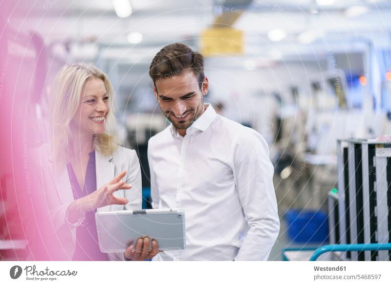 Smiling businesswoman discussing with young male colleague in illuminated factory color image colour image indoors indoor shot indoor shots interior