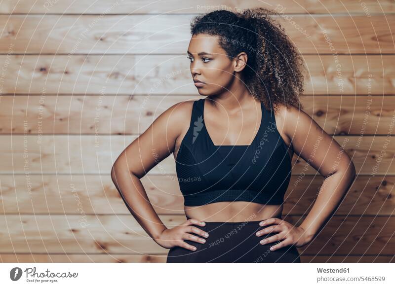 Portrait of confident athletic young woman standing at wooden wall human human being human beings humans person persons Mixed Race mixed race ethnicity