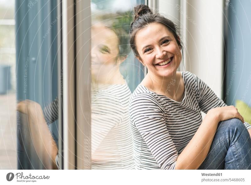 Portrait of happy woman sitting at the window at home portrait portraits windows Seated females women happiness Adults grown-ups grownups adult people persons