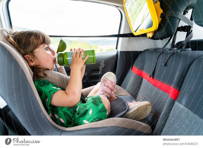 Toddler girl sitting on a car seat with a mirror drinking water human human being human beings humans person persons caucasian appearance caucasian ethnicity