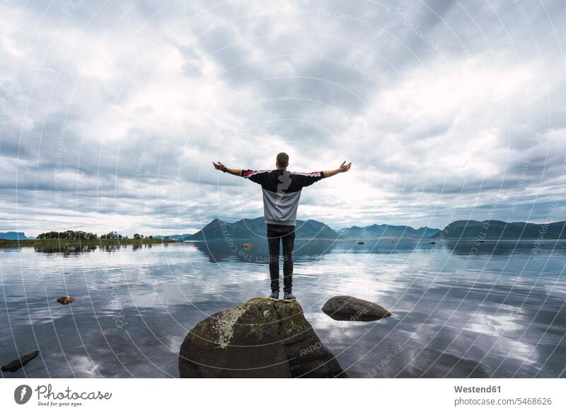 Norway, Senja island, rear view of man standing on a rock at the coast men males rocks coastline shoreline Adults grown-ups grownups adult people persons