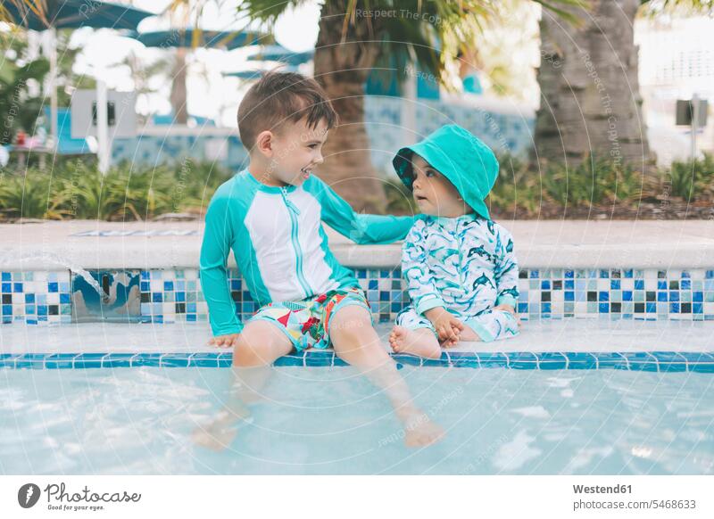Happy little brothers at a swimming pool smile Seated sit summer time summertime summery relax relaxing relaxation delight enjoyment Pleasant pleasure