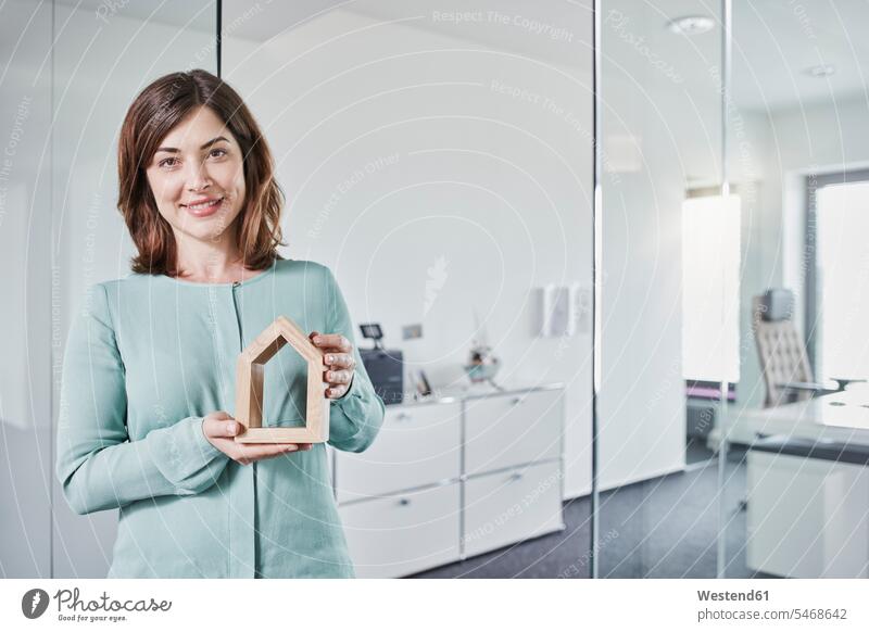 Portrait of smiling young businesswoman holding architectural model in office portrait portraits Architectural Model offices office room office rooms